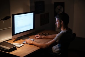 Handsome young man sitting in dark room and using computer
