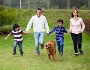 Happy family running outdoors chasing a dog