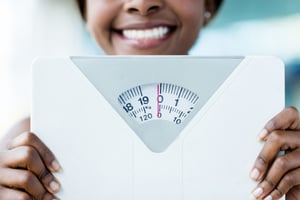 Happy woman holding a weight scale at the gym-1