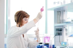 Женщина-медик измеряет жидкость Эрленмейера в лаборатории