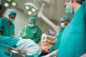 Surgeon holding a mask on the face of a woman in a surgical room