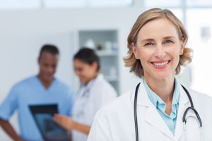 Woman doctor smiling and looking to the camera while a medical team is working