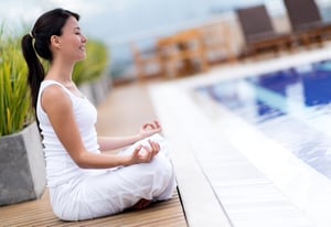 Yoga woman meditating by the pool looking very relaxed