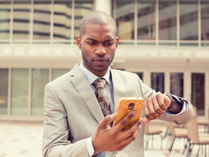 Young business man looking at his mobile phone wrist watch running out of time