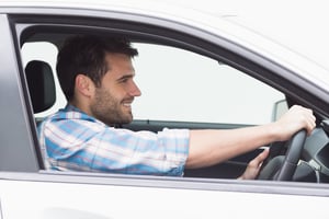 Young man driving and smiling in his car